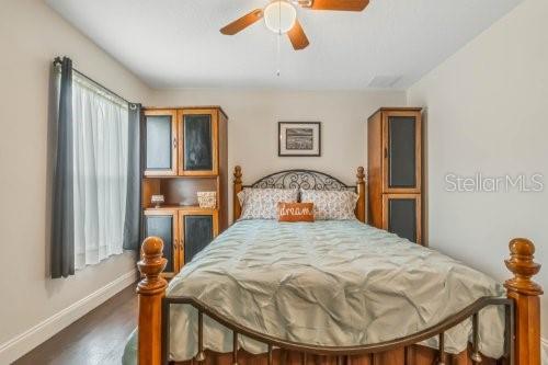 bedroom with wood finished floors, a ceiling fan, and baseboards