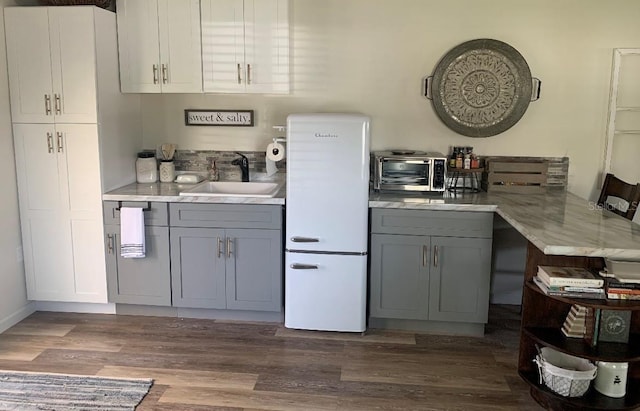 kitchen featuring dark wood-type flooring, light countertops, a sink, and gray cabinetry