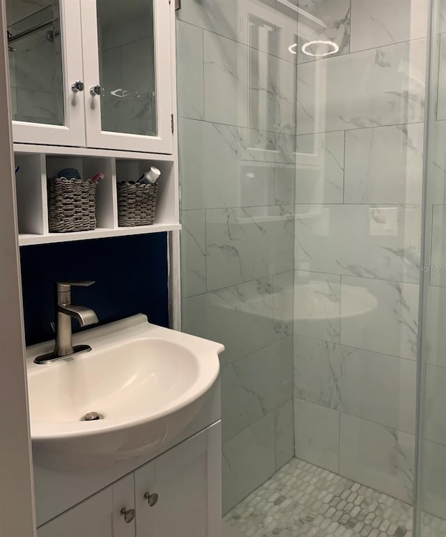 full bathroom featuring tiled shower and vanity