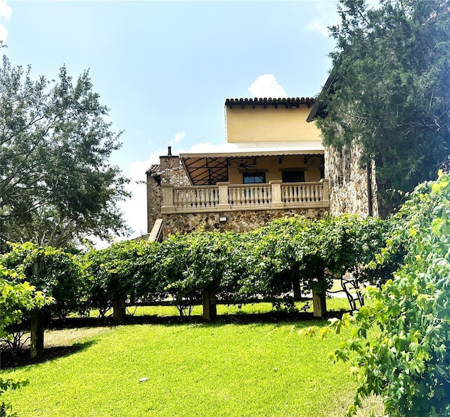 rear view of house featuring a yard, a balcony, and ceiling fan