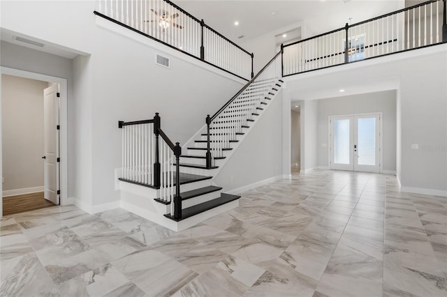 stairs featuring french doors and a towering ceiling