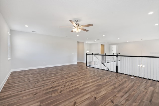 empty room with wood-type flooring and ceiling fan with notable chandelier