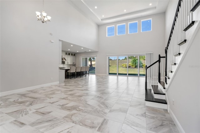 entrance foyer with a notable chandelier, a towering ceiling, and a tray ceiling