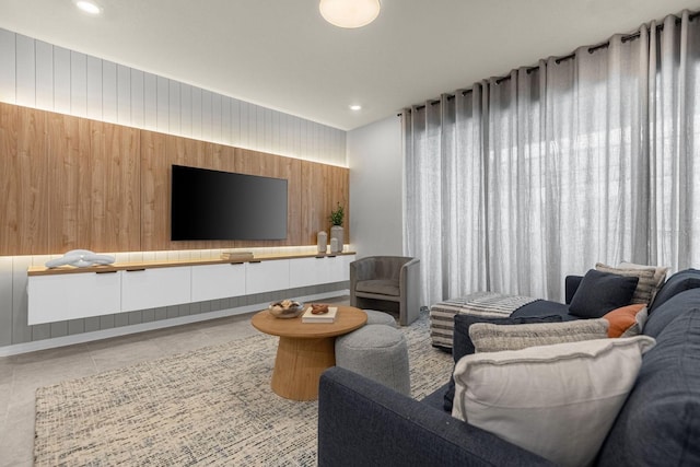 living room with light tile patterned floors and wood walls