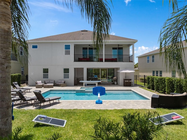 back of property featuring a yard, ceiling fan, a balcony, and an outdoor living space