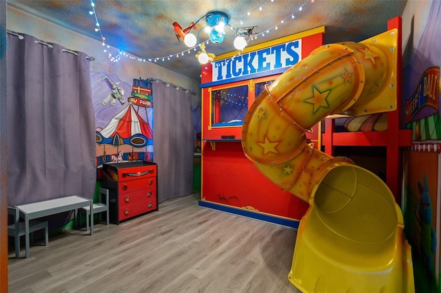 playroom featuring light hardwood / wood-style flooring and a textured ceiling