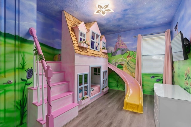 playroom featuring light hardwood / wood-style floors and a textured ceiling