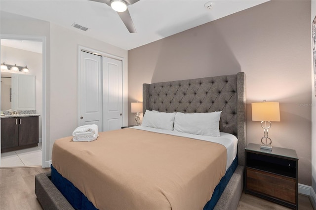 bedroom with ceiling fan, light hardwood / wood-style floors, a closet, and ensuite bathroom