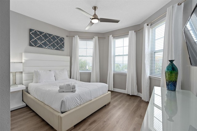 bedroom with a textured ceiling, light wood-type flooring, and ceiling fan