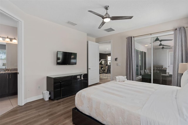 bedroom with access to exterior, ensuite bathroom, a textured ceiling, ceiling fan, and hardwood / wood-style flooring