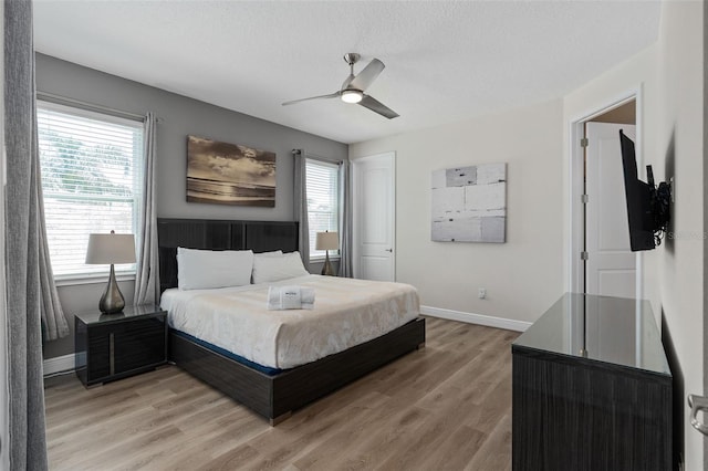 bedroom featuring hardwood / wood-style floors, ceiling fan, a textured ceiling, and multiple windows