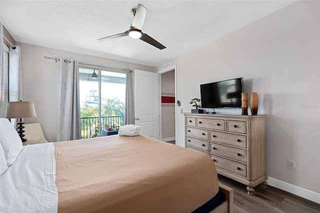 bedroom with ceiling fan, dark hardwood / wood-style flooring, a textured ceiling, and access to outside