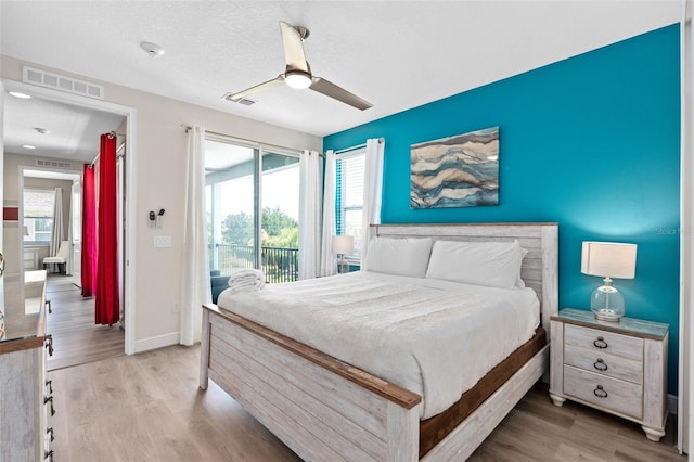 bedroom featuring access to exterior, light hardwood / wood-style floors, multiple windows, and ceiling fan