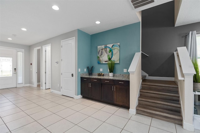 kitchen with light stone countertops, dark brown cabinetry, and light hardwood / wood-style flooring