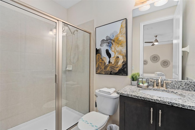 bathroom with ceiling fan, a shower with door, vanity, and toilet