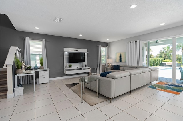 living room featuring ceiling fan, light tile patterned floors, and a textured ceiling