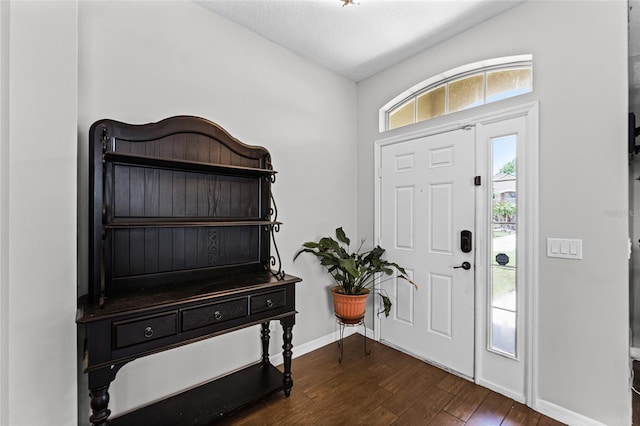 foyer with dark wood-type flooring and baseboards