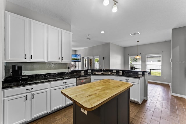 kitchen featuring visible vents, stainless steel dishwasher, white cabinetry, a kitchen island, and a peninsula