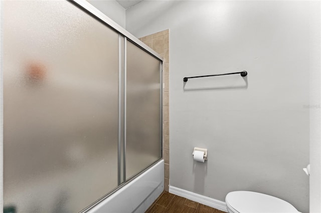 bathroom with toilet, shower / bath combination with glass door, baseboards, and wood finished floors