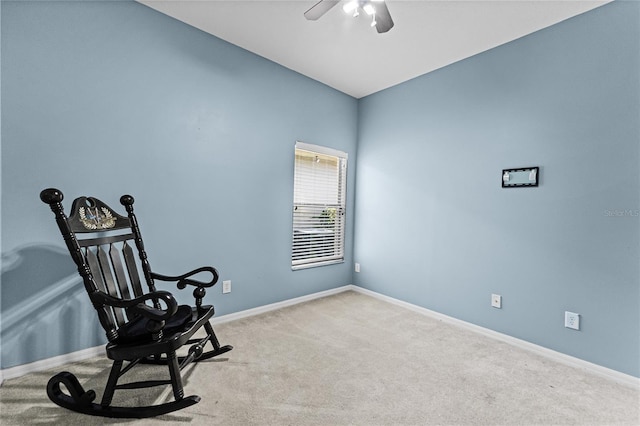 living area with ceiling fan, baseboards, and light colored carpet