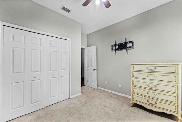 unfurnished bedroom featuring baseboards, visible vents, a ceiling fan, light colored carpet, and a closet