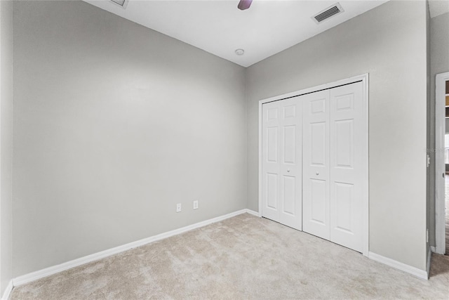 unfurnished bedroom featuring baseboards, visible vents, a closet, and light colored carpet