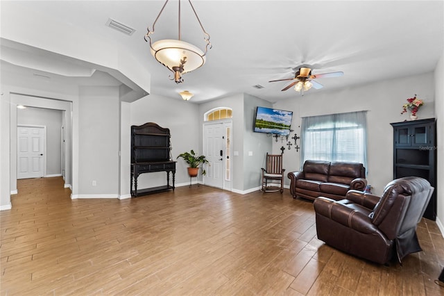 living area with a ceiling fan, baseboards, visible vents, and wood finished floors