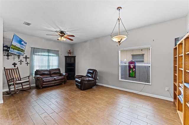 sitting room featuring baseboards, wood finished floors, visible vents, and a ceiling fan