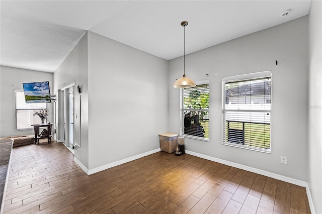 unfurnished dining area with dark wood-style flooring and baseboards