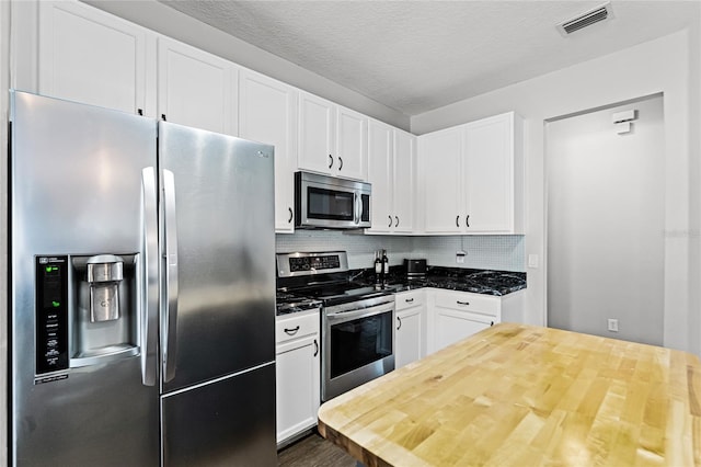 kitchen featuring stainless steel appliances, white cabinetry, and visible vents