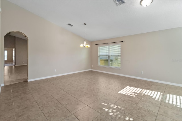 tiled spare room featuring an inviting chandelier and vaulted ceiling