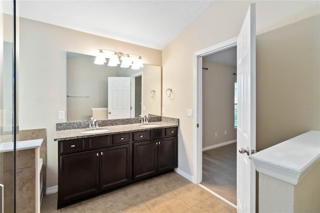 bathroom with tile patterned flooring, a textured ceiling, vanity, and lofted ceiling