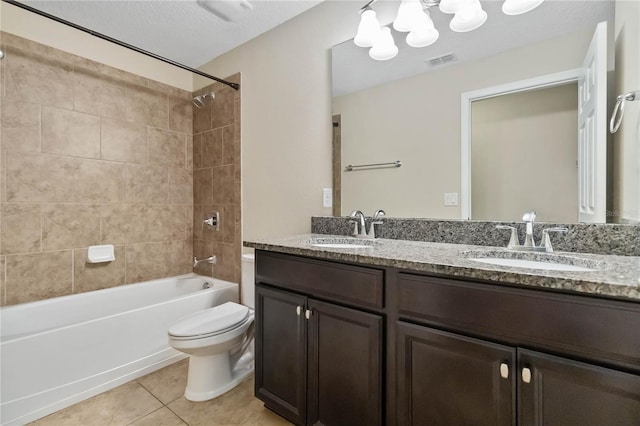 full bathroom with vanity, tile patterned floors, tiled shower / bath, toilet, and a textured ceiling