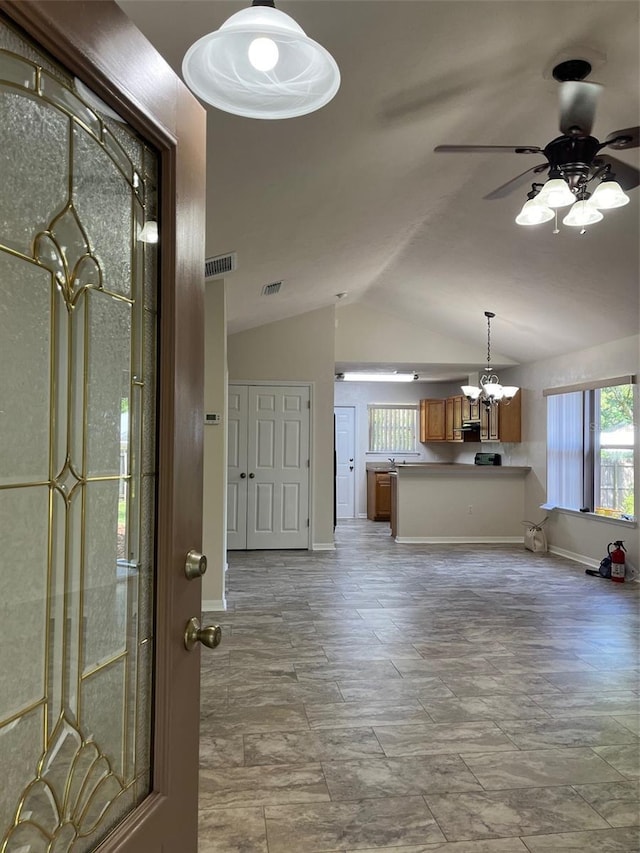 entrance foyer with ceiling fan with notable chandelier and vaulted ceiling