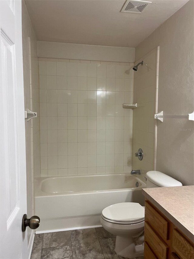 full bathroom with tiled shower / bath, vanity, and toilet