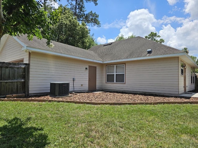 back of house with central AC and a lawn