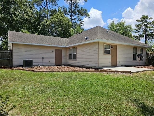 rear view of house featuring central AC unit and a lawn