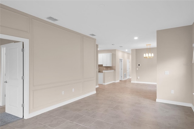 unfurnished room with a chandelier and light tile floors