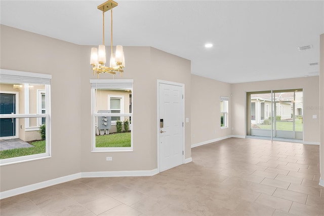 tiled empty room featuring a notable chandelier