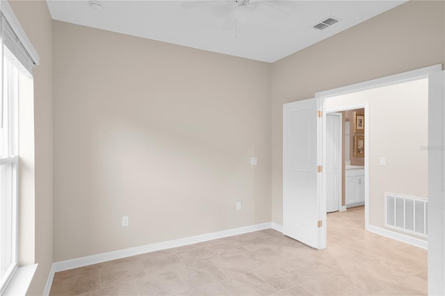 empty room with plenty of natural light, ceiling fan, and light tile floors