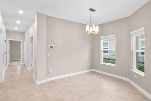 empty room with a notable chandelier and light tile floors