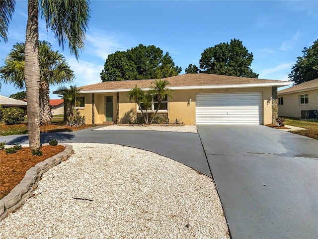 single story home with central AC unit and a garage