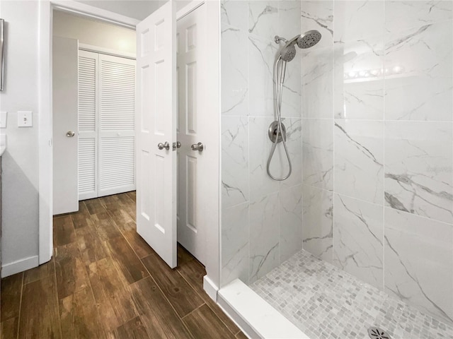 bathroom with tiled shower and hardwood / wood-style flooring