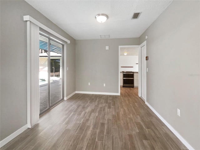 empty room featuring a textured ceiling, wine cooler, and dark wood-type flooring