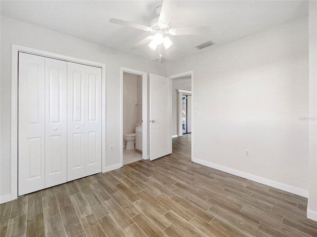 unfurnished bedroom featuring a closet, ceiling fan, hardwood / wood-style floors, and ensuite bath