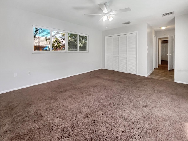 unfurnished bedroom with ceiling fan, a closet, and dark carpet