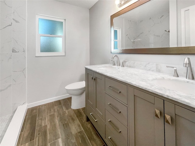 bathroom featuring tiled shower, hardwood / wood-style floors, vanity, and toilet