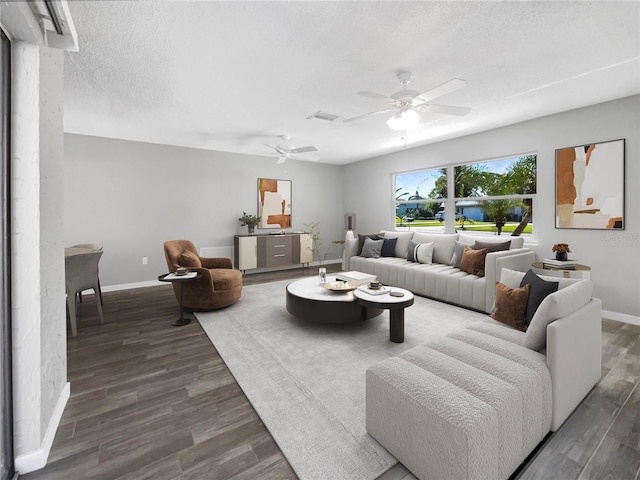 living room with a textured ceiling, dark hardwood / wood-style flooring, and ceiling fan