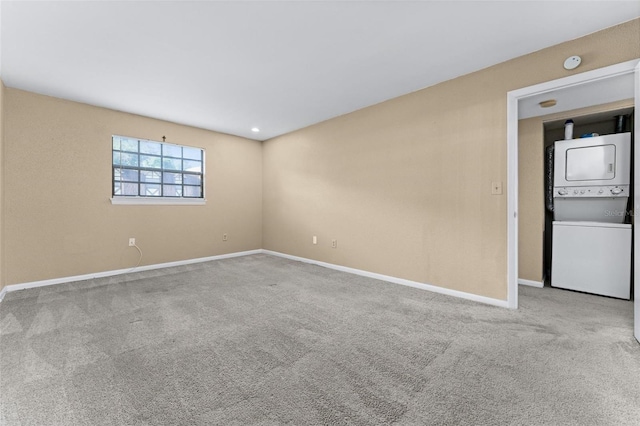 carpeted spare room featuring stacked washer / drying machine