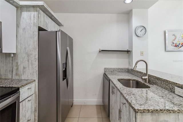 kitchen with light stone countertops, sink, stainless steel appliances, and light tile patterned flooring